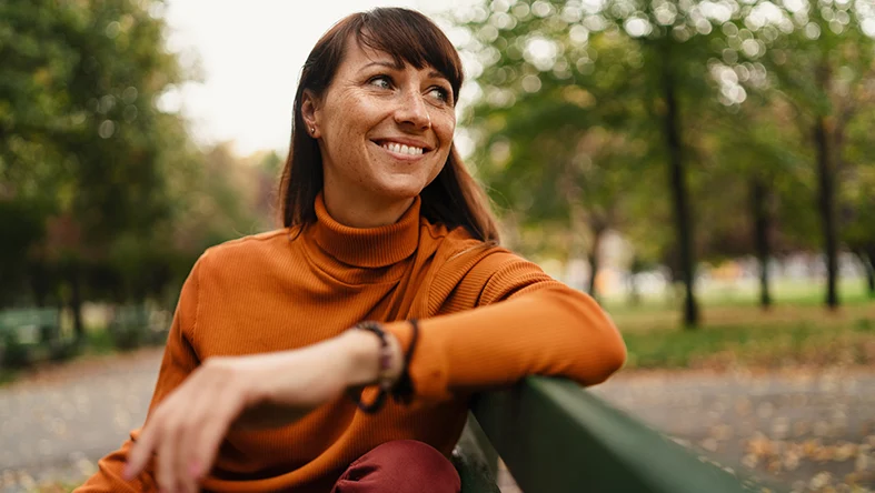 A woman smiles to the side as she thinks about health insurance